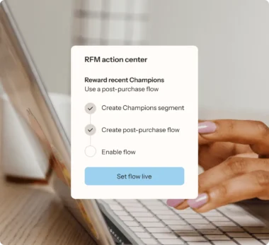 Close-up of hands on a laptop keyboard with an overlay showing "RFM action center" options for creating segments and flows.