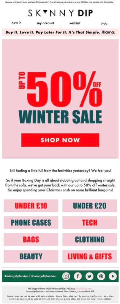 Image shows a Boxing Day marketing email from lifestyle fashion brand Skinnydip London, featuring bright red and blue font on a millennial pink background that reads, “up to 50% off winter sale.” The prominent CTA button reads, “shop now.”