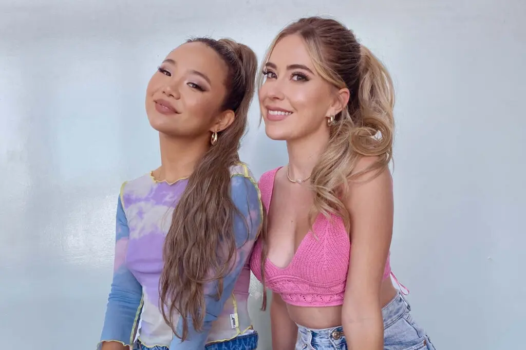 Two women sitting next to each other smiling at the camera.