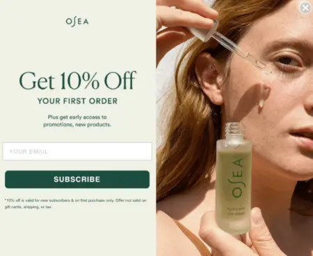 Image shows an email pop-up from vegan skincare brand OSEA, featuring the sign-up details and form fields on the left against a pale green background, and on the right, a close-up photo of a woman putting oil on her face with a dropper.