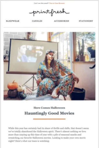 Image shows the top of a Halloween marketing email from luxury pajama brand Printfresh, featuring a photo of one of their team members wearing their pajamas with a movie projector screen in the background. The email headline reads, “Here comes Halloween: hauntingly good movies.”