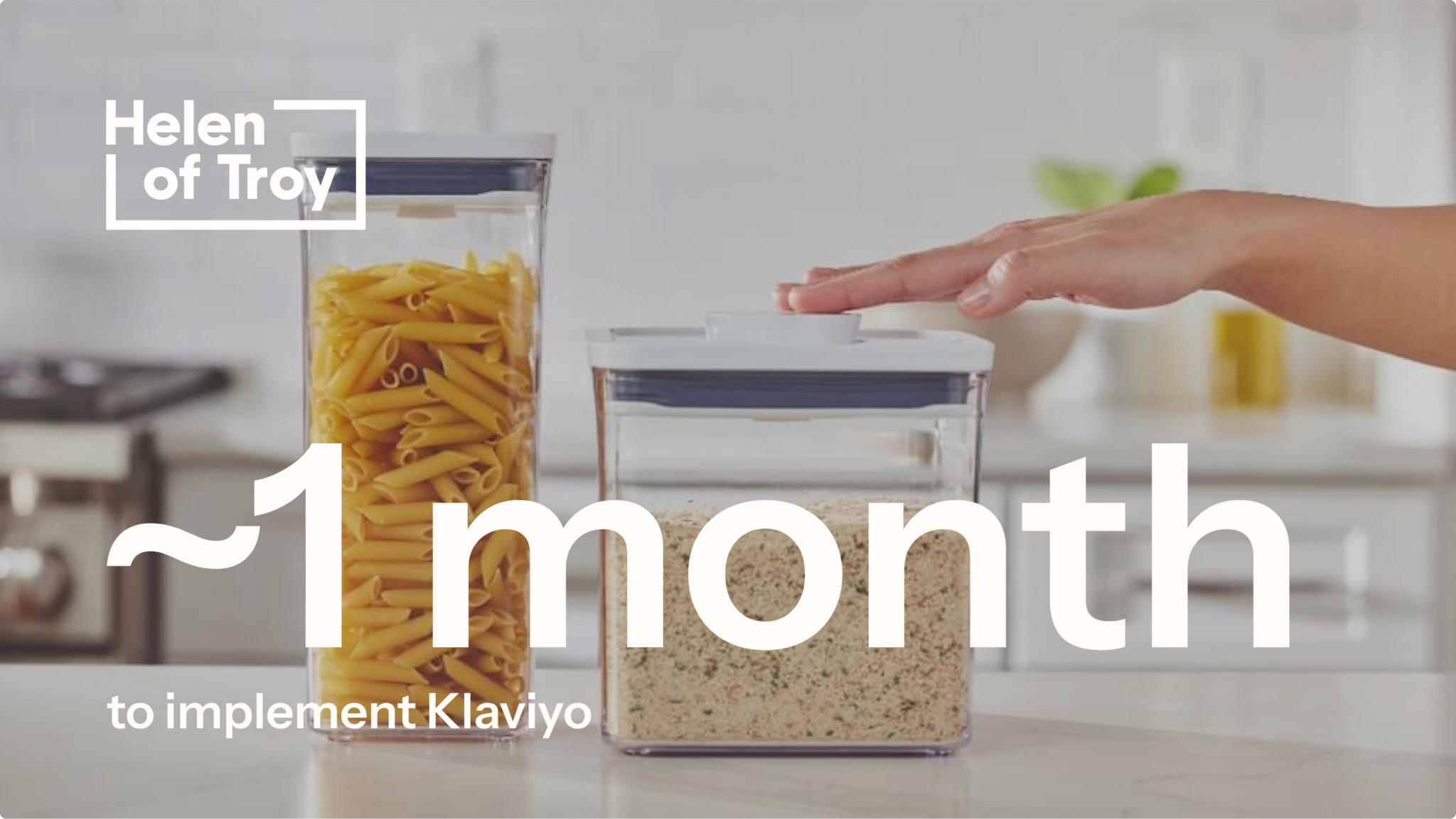 Two food storage containers, one filled with pasta and the other with grains, on a kitchen countertop with a hand pressing the lid. Text overlay states '~1 month to implement Klaviyo,' showcasing Helen of Troy’s Klaviyo adoption timeline.